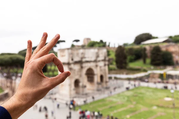 ROME, ITALY - JUNE 28, 2019: partial view of man showing okay sign in front of arch of constantine — Stock Photo
