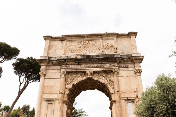 ROMA, ITÁLIA - 28 DE JUNHO DE 2019: Arco de Tito e árvores verdes sob céu cinzento — Fotografia de Stock