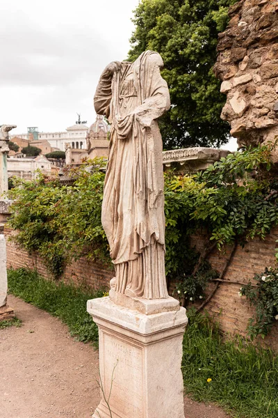 ROME, ITALY - JUNE 28, 2019: ancient headless statue near old wall and green plants — Stock Photo
