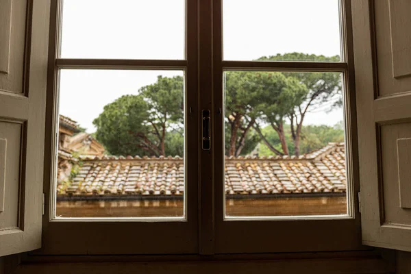 Techo y árboles verdes detrás de la ventana en roma, italia - foto de stock