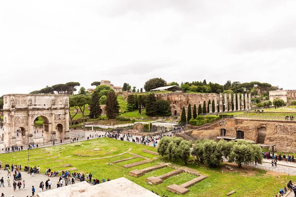 ROMA, ITALIA - 28 DE JUNIO DE 2019: turistas caminando en foro romano con edificios antiguos - foto de stock