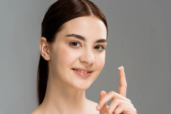 Весела гола жінка з косметичним кремом в пальці ізольована на сірому — стокове фото