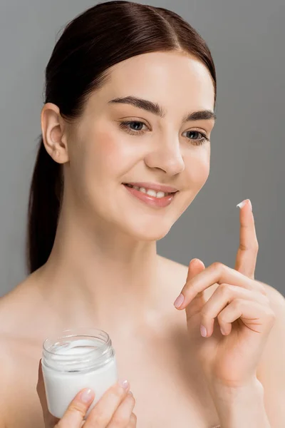 Happy naked woman holding container with cosmetic cream isolated on grey — Stock Photo