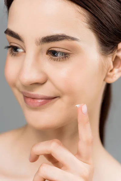 Gros plan de femme nue heureuse avec crème cosmétique au doigt isolé sur gris — Photo de stock