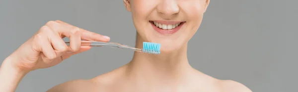 Panoramic shot of happy naked woman holding toothbrush near teeth isolated on grey — Stock Photo