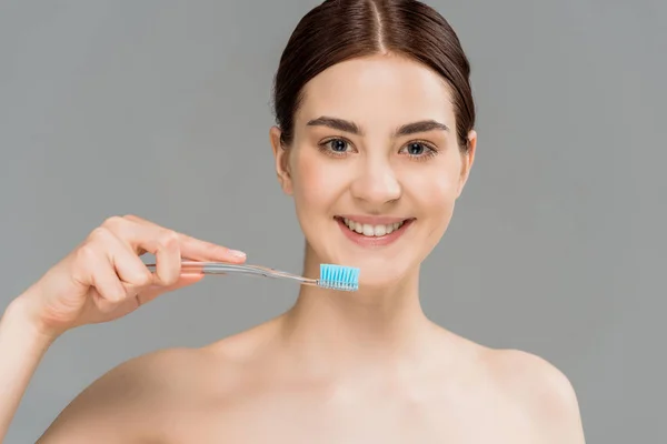 Happy naked woman holding toothbrush near teeth isolated on grey — Stock Photo