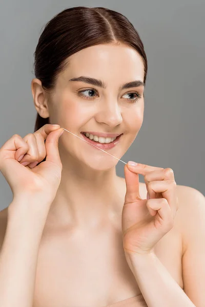 Cheerful woman holding dental floss near teeth and smiling isolated on grey — Stock Photo