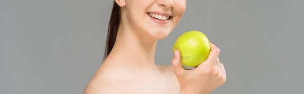 Панорамний знімок щасливої жінки, посміхаючись, тримаючи зелене яблуко ізольовано на сірому — стокове фото