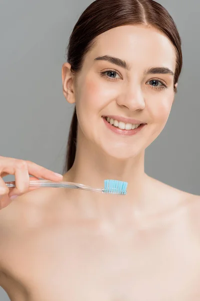 Alegre mujer desnuda sosteniendo cepillo de dientes mientras sonríe aislado en gris - foto de stock