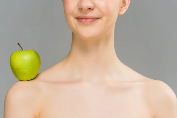 Обрезанный вид обнаженной женщины с зеленым яблоком на плече улыбается изолированы на серый — стоковое фото