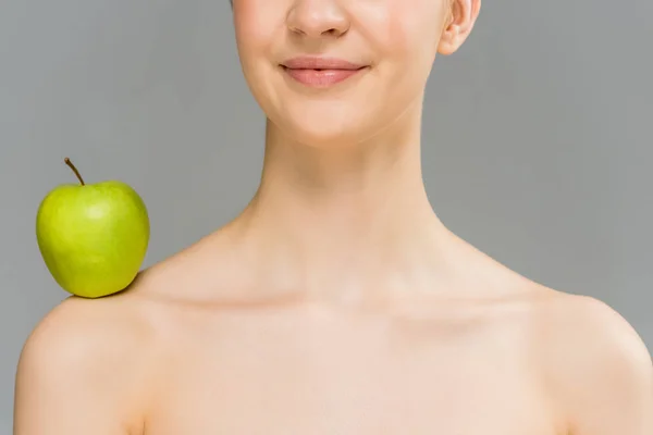 Cropped view of nude woman with green apple on shoulder smiling isolated on grey — Stock Photo