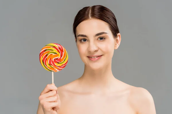 Cheerful naked woman holding colorful lollipop isolated on grey — Stock Photo