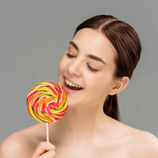 Cheerful naked woman looking at colorful lollipop isolated on grey — Stock Photo