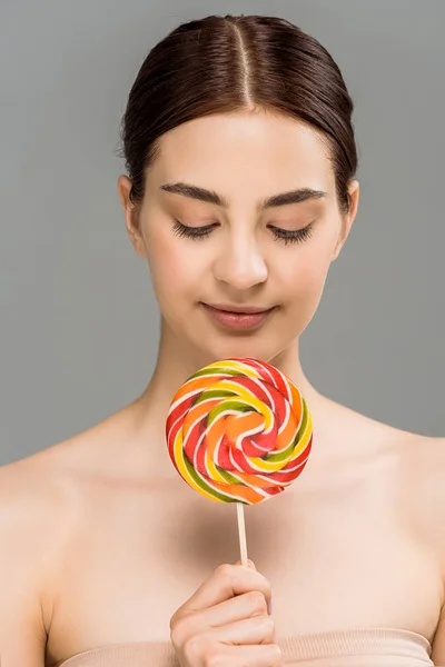 Cheerful young woman holding colorful lollipop isolated on grey — Stock Photo