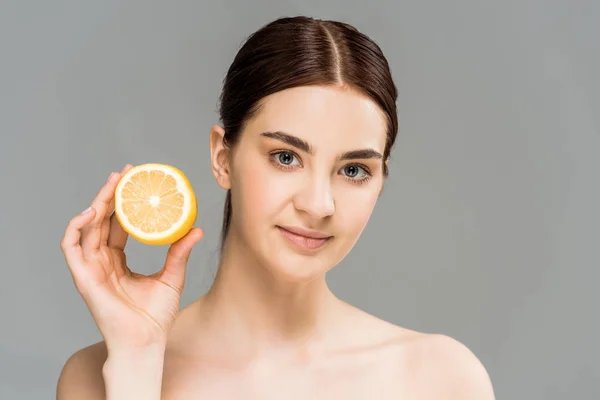 Приваблива гола дівчина тримає половину лимона ізольовано на сірому — стокове фото