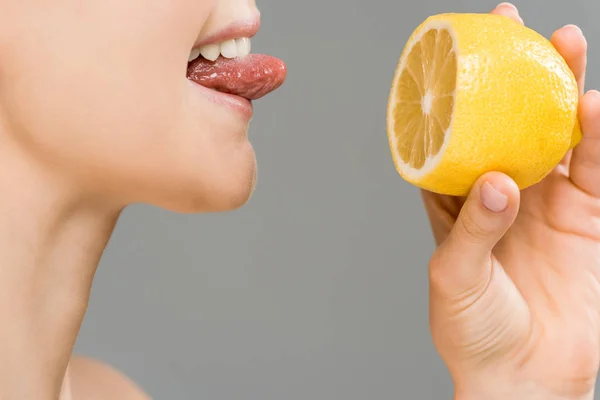 Обрізаний вид веселої дівчини, що тримає половину лимона ізольовано на сірому — стокове фото