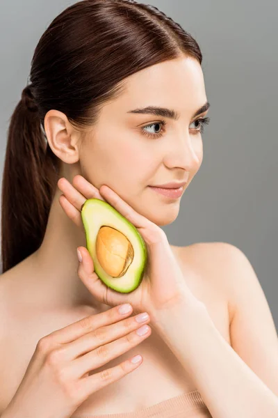 Schöne junge Frau mit Avocado halb isoliert auf grau — Stockfoto