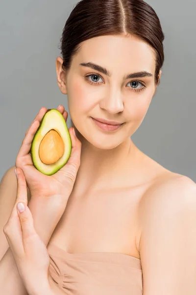 Усміхнена молода жінка тримає половину авокадо ізольовано на сірому — Stock Photo