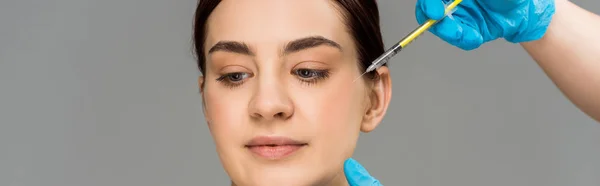 Panoramaaufnahme eines plastischen Chirurgen, der Frau eine Schönheitsinjektion macht, isoliert auf grau — Stockfoto