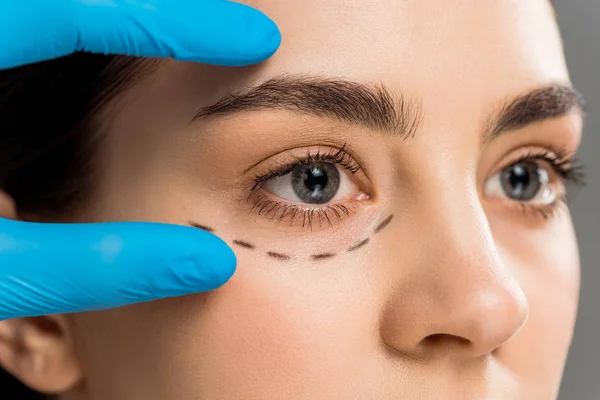 Ausgeschnittene Ansicht des plastischen Chirurgen im Latex-Handschuh berührt Gesicht der Frau isoliert auf grau — Stockfoto