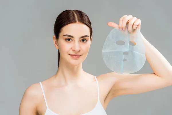 Allegra donna bruna che tiene la maschera isolata sul grigio — Foto stock