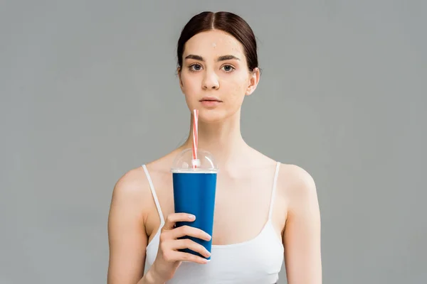 Jeune femme brune avec problème de peau tenant tasse en plastique isolé sur gris — Photo de stock