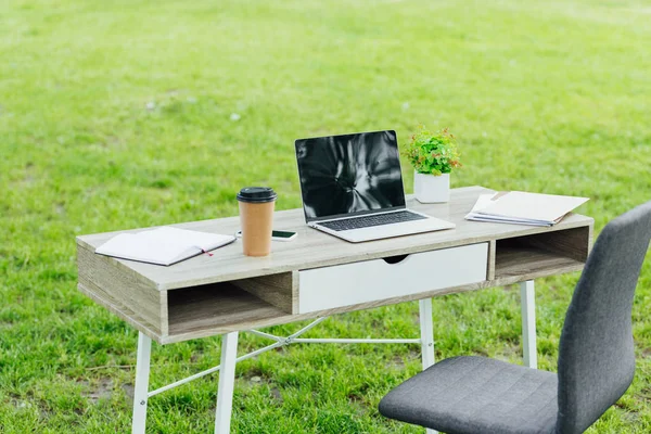 Mesa de oficina con diferentes cosas de oficina cerca de la silla de oficina en el parque - foto de stock