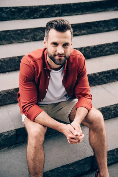 Junger Mann sitzt auf Steintreppe und blickt in Kamera — Stockfoto