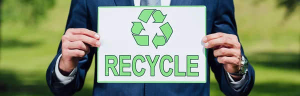 Panoramic shot of man holding card with recycle inscription — Stock Photo