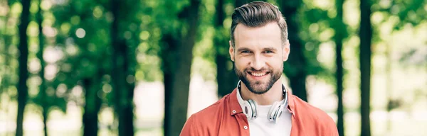 Panoramic shot of man with headphones smiling and looking at camera — Stock Photo