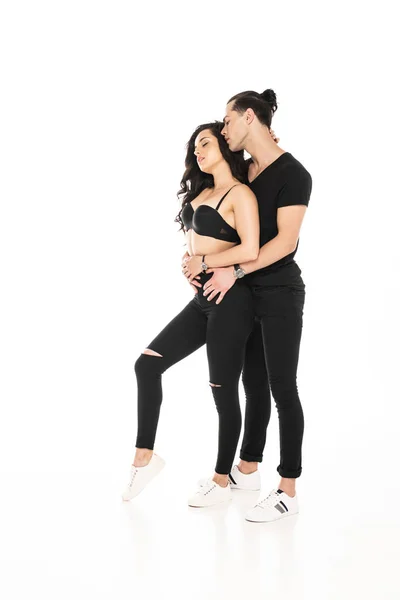 Vista completa de pareja en ropa negra abrazando aislado en blanco - foto de stock