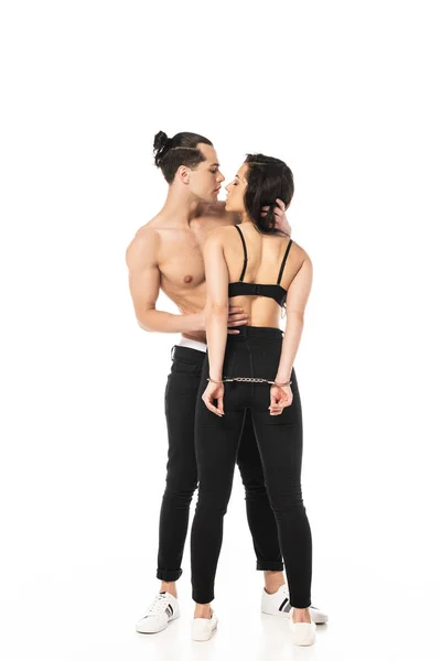 Full length view of shirtless man embracing sexy girlfriend in handcuffs isolated on white — Stock Photo