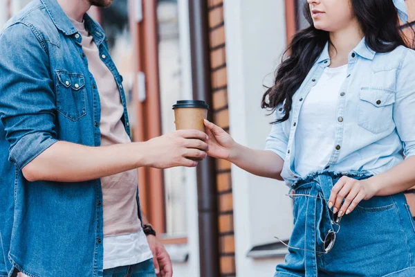 Cropped view of man giving paper cup to woman while standing outside — Stock Photo