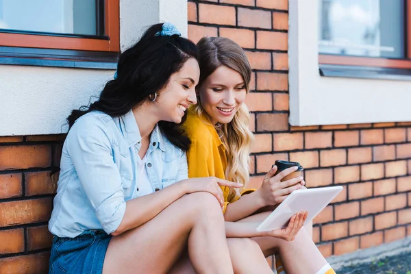 Glückliche Frau zeigt mit Finger auf digitales Tablet in der Nähe von Mädchen — Stockfoto