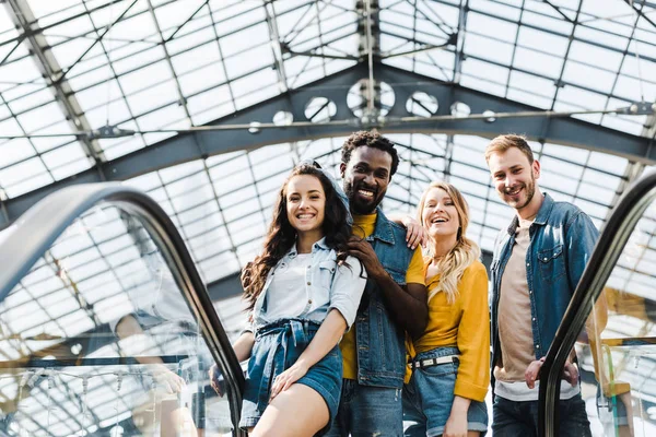 Niedrigwinkel-Ansicht glücklicher multikultureller Freunde, die lächelnd in die Kamera schauen — Stockfoto