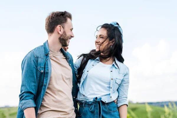 Fröhliches und attraktives Mädchen lächelt, während es den gutaussehenden Mann ansieht — Stockfoto