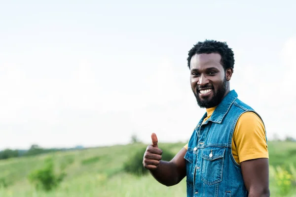 Homme afro-américain joyeux debout et montrant pouce vers le haut — Photo de stock