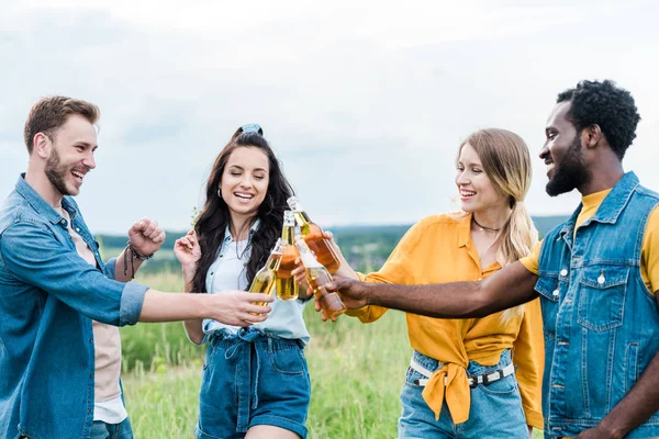 Happy multicultural men and women clinking bottles with beer — Stock Photo