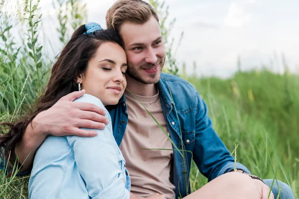 Весела молода жінка сидить з красивим чоловіком на зеленій траві — стокове фото