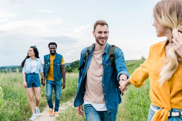 Selective focus of woman holding hands with man near multicultural friends — Stock Photo