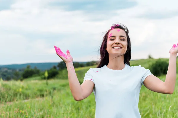 Heureuse jeune femme debout avec les yeux fermés et de la poudre rose sur les mains — Photo de stock