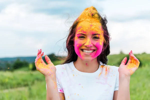 Donna felice con vernice holi rosa e gialla sul viso — Foto stock