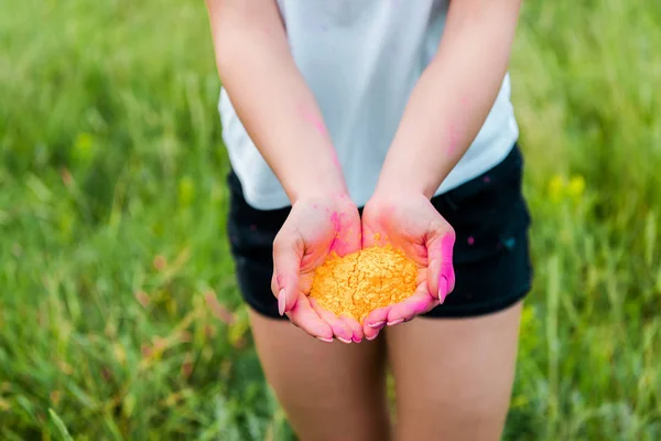 Selektiver Fokus einer jungen Frau mit gelber Holi-Farbe in den Händen — Stockfoto