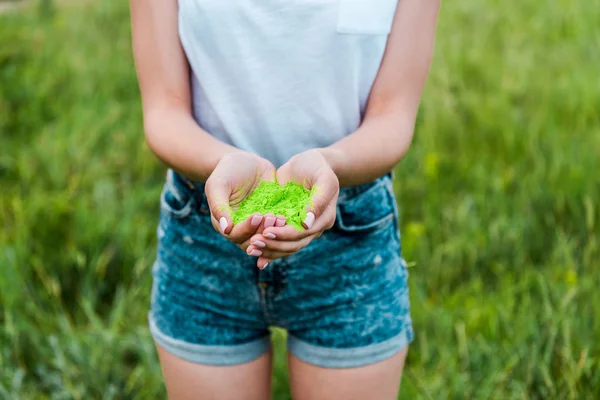 Vue recadrée de la jeune femme tenant vert holi peinture dans les mains — Photo de stock