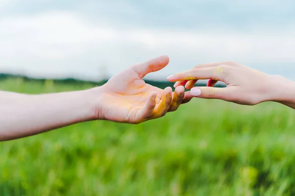 Vista ritagliata di giovane uomo e donna con vernice gialla holi sulle mani — Foto stock