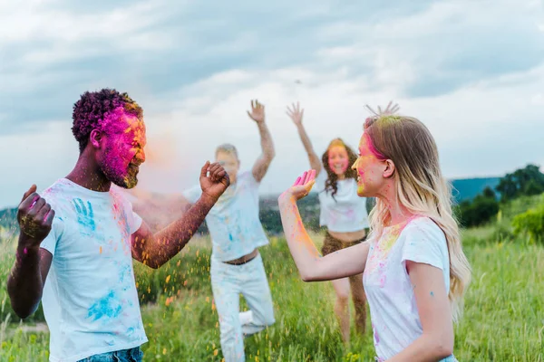 Selektiver Fokus multikultureller Freunde mit bunten Holi-Farben auf Gesichtern — Stockfoto