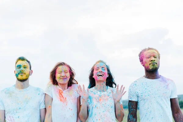 Schöner afrikanisch-amerikanischer Mann und fröhliche Freunde mit Holi-Farben auf den Gesichtern und geschlossenen Augen — Stockfoto