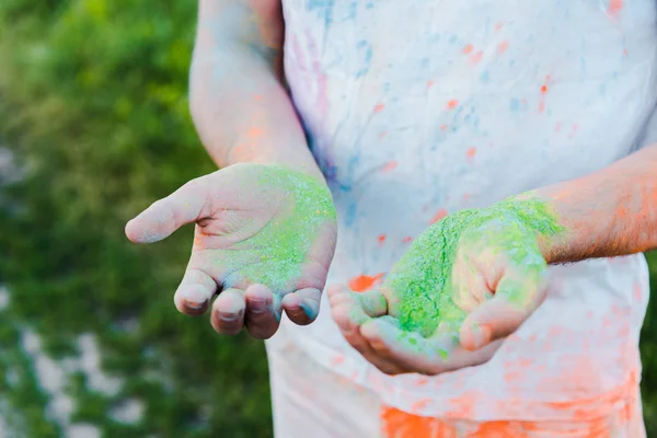 Cropped view of young man with holi paints on hands — Stock Photo