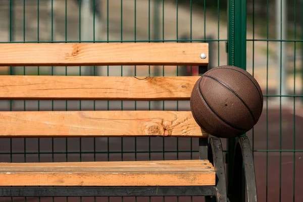 Brauner Basketballball auf Holzbank am Basketballplatz — Stockfoto