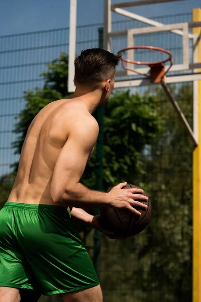 Vista posterior del entrenamiento de jugador de baloncesto con pelota en la cancha de baloncesto en día soleado - foto de stock